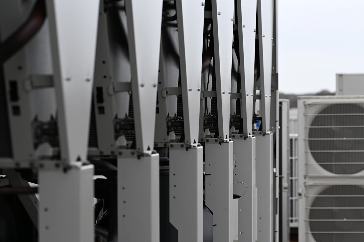 A row of large rooftop condensing units seen end-on along the roof of a building.