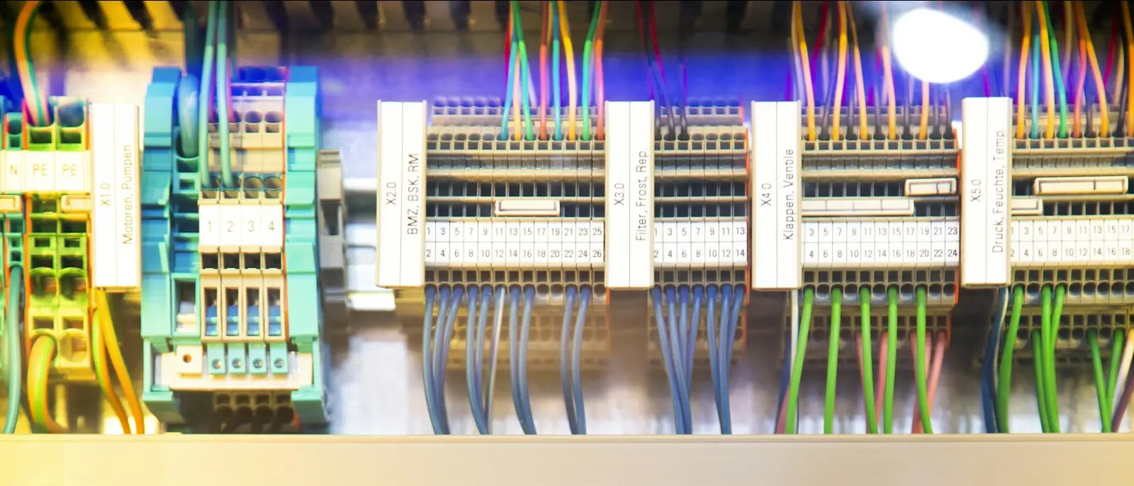A long rail of terminal blocks and breakers in an open cabinet, ranks of numbered conductors running down from them.