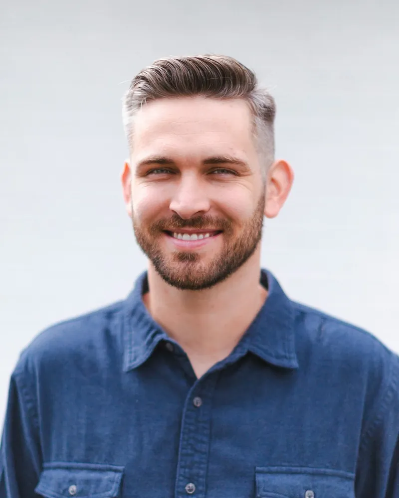 A bearded HVAC technician in a denim work shirt, looking straight at the camera.
