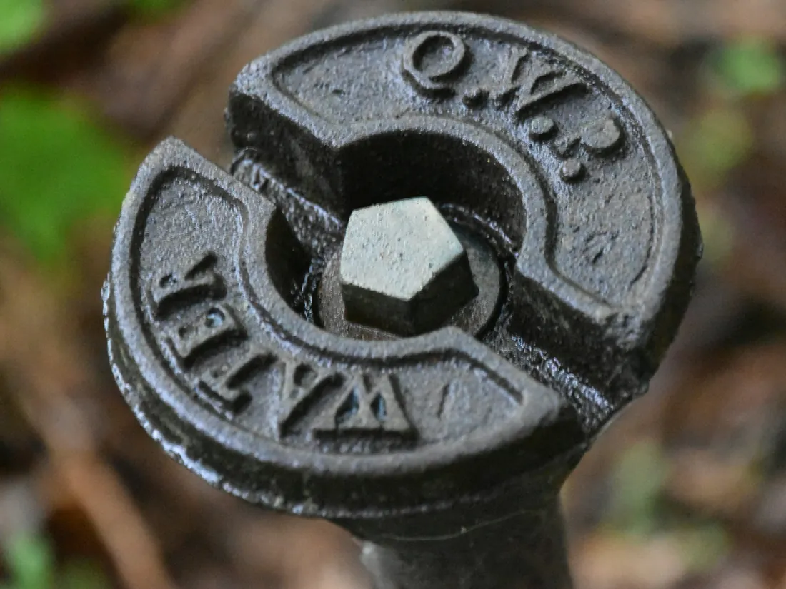A cast-iron water service cover at the kerb, the word WATER cast into its face.